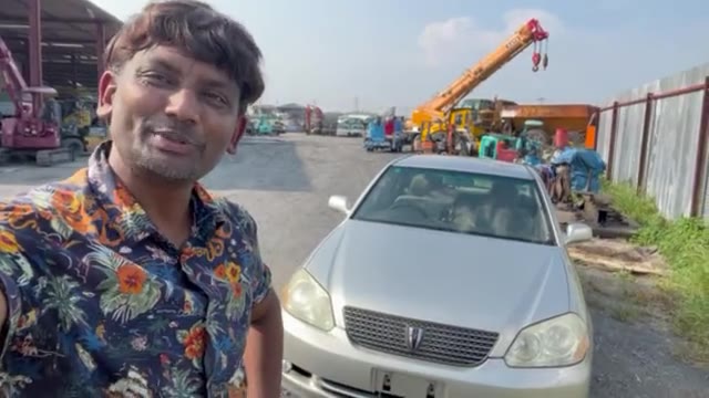 Walking a Japanese auction yard past cars and heavy machinery